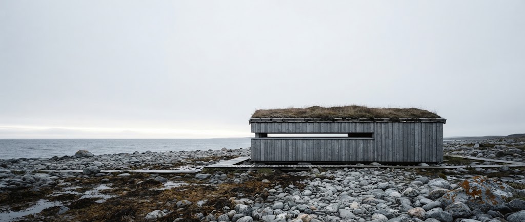 Artist's impression of a planned low timber hide on the stony shore, with a narrow window slot facing the sea and a wide sky